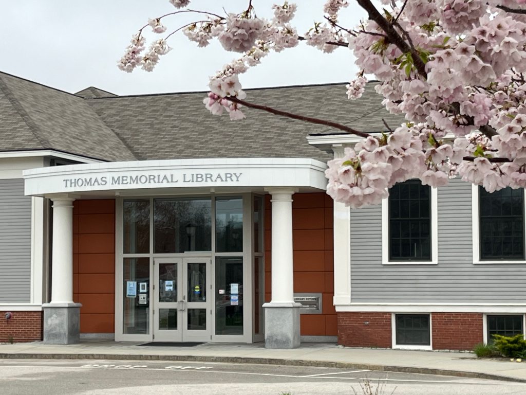 A photograph of the library with pink crabapple blossoms in the foreground.