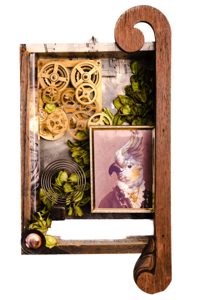 A photo of a three dimensional work of art featuring a small framed photograph of a cockatoo wearing a suit in the bottom left-hand corner, a set of gold-colored gears in the upper right-hand corner, and green leaves throughout.