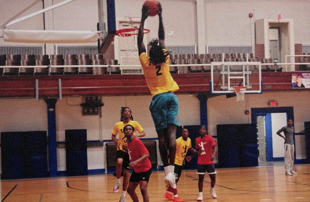 A photo of a young man dunking basketball while suspended in midair