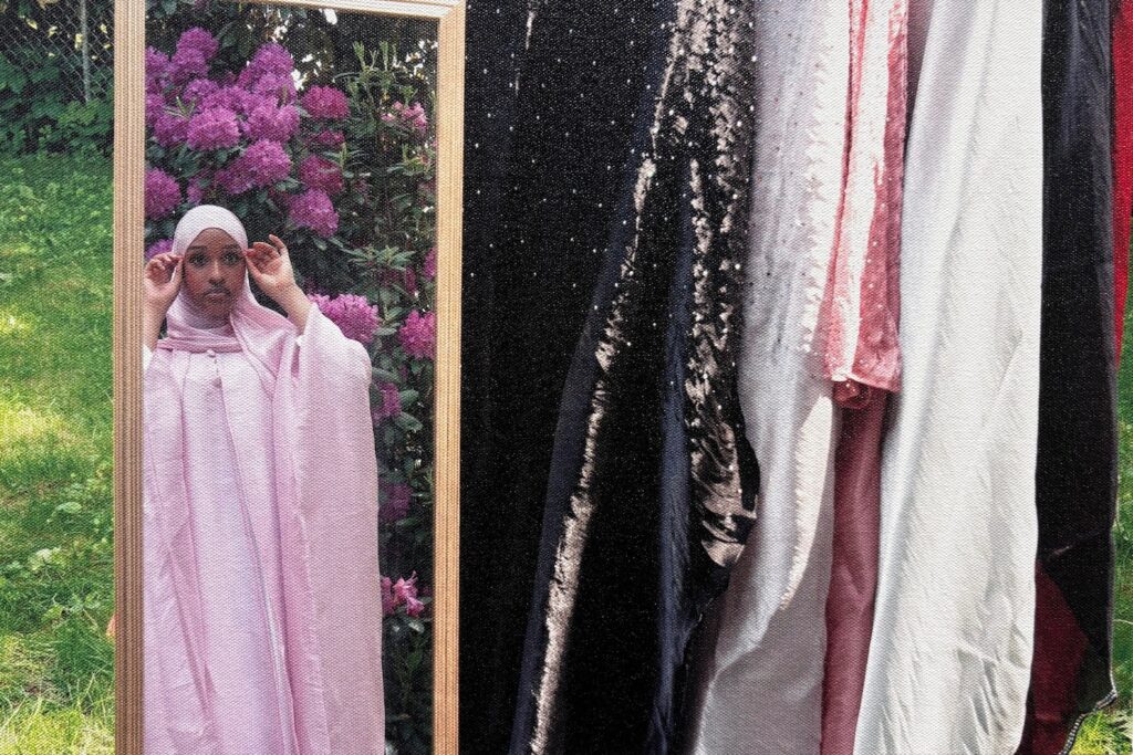a photo of a young woman wearing a pale pink burka viewing herself in a mirro outdoors