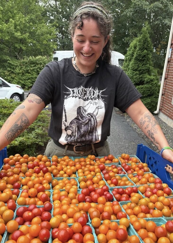 a woman wholding a tray of bright red cherry tomatoes