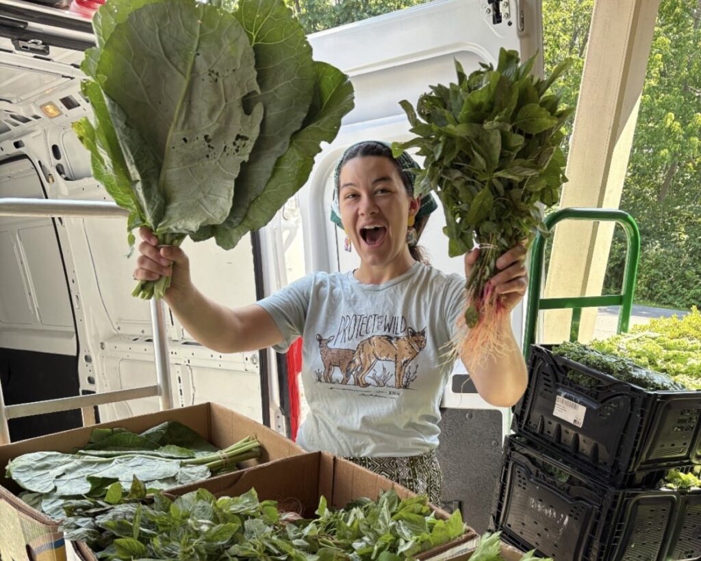a woman holds up two heads of lettuce and smiles
