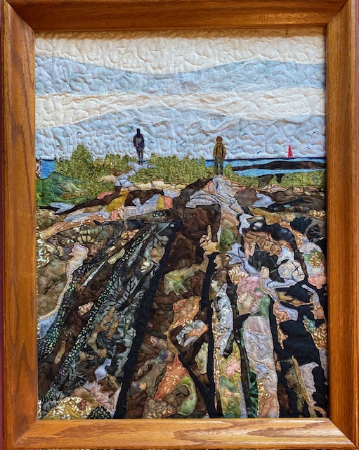 a quilt featuring people standing in a rocky landscape